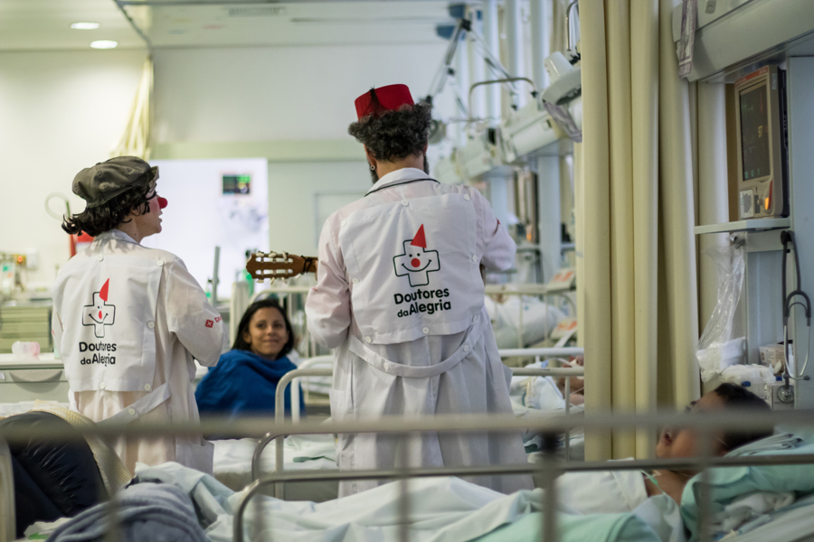 dois palhaços interagindo com uma criança e sua mãe dentro da UTI de um hospital